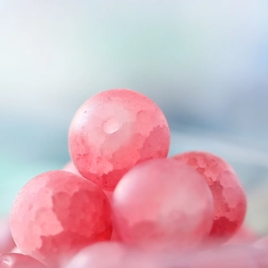 Macro view of 10mm frosted pink glass beads with ice crack texture for DIY jewelry