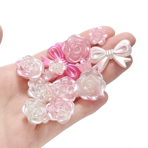 Macro-opname van parelmoer roze en witte hars bloem- en strikkralen voor DIY-projecten