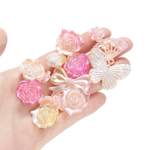 Detailopname van parelmoer harsbedeltjes met rozen en strikken voor DIY-sieraden