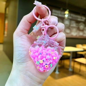 Detailed view of pink strawberry shaker keychain with liquid glitter and small bell