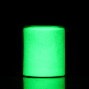 Glow-in-the-dark luminous powder container emitting intense green light in dark setting