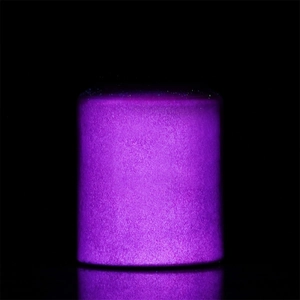 Detailed view of vibrant purple luminous powder glowing in a clear container