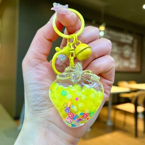 Detailed close-up of yellow strawberry oil bottle keychain with beads and sequins