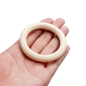 Natural wood ring for DIY crafts held in hand to show size on white background