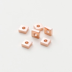 Detalle macro de seis cuentas espaciadoras cuadradas pulidas en oro rosa de 18k para DIY