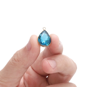 Colgante de cristal azul en forma de gota con borde dorado mostrado para tamaño