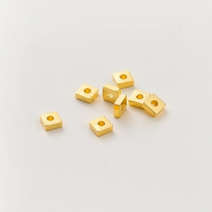 Vista macro de cuentas espaciadoras cuadradas bañadas en oro de 18k para joyería hecha a mano