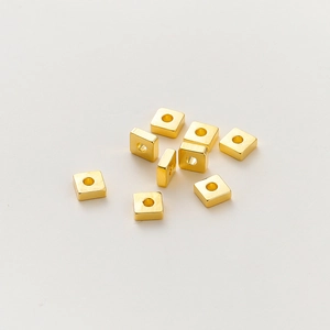 Macro de 10 cuentas cuadradas de metal chapado en oro con agujeros centrales en fondo blanco