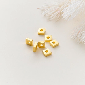 Vista macro de cuentas cuadradas de metal bañadas en oro 18k para manualidades DIY