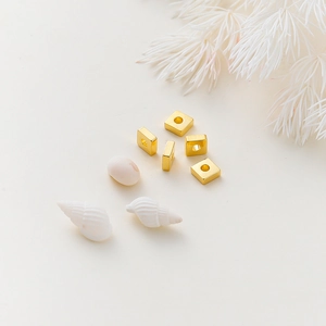 Detalle macro de cuentas cuadradas bañadas en oro de 18k para joyería DIY con acabado