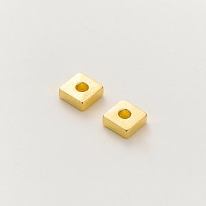 Detalle macro de cuentas espaciadoras cuadradas bañadas en oro de 18k con acabado cepillado
