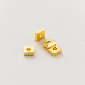 Detalle macro de 4 cuentas espaciadoras cuadradas planas de oro de 18k con agujero central