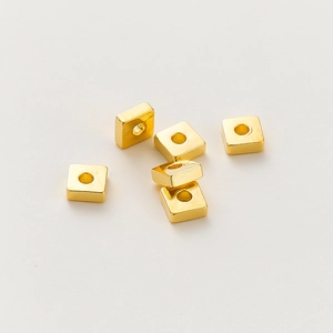 Detalle macro de seis cuentas espaciadoras cuadradas bañadas en oro de 18k para joyería DIY