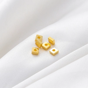 Primer plano de cuentas espaciadoras cuadradas bañadas en oro de 18k con textura cepillada