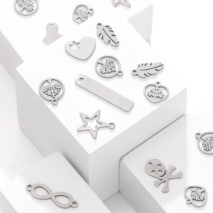 Edelstahl-DIY-Anhänger mit Herz-, Totenkopf- und Baummotiven auf weißen Dekowürfeln