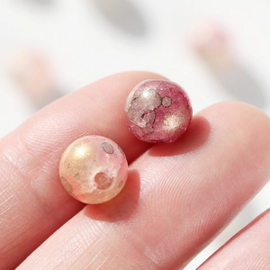 Vue macro de perles en verre marbré de 10mm avec feuille d'or sur le bout des doigts