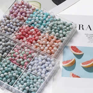 Détail de perles en verre marbré de 10mm rangées dans une boîte de rangement plastique