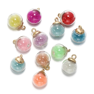 Gros plan de pendentifs boules de verre colorées avec micro-perles et boucles dorées pour bijoux