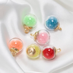 Vue détaillée de pendentifs boules en verre coloré avec attaches dorées sur soie