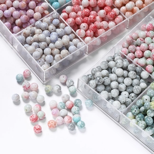 Détail macro de perles en verre marbré 10mm dans une boîte pour création de bijoux DIY