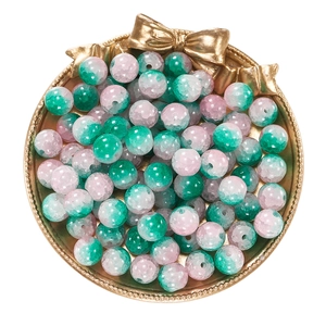 Detailed view of 10mm pink and green cracked glass beads in a gold decorative tray