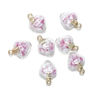 Vue détaillée de pendentifs cœur en verre avec pierres roses et capuchons dorés