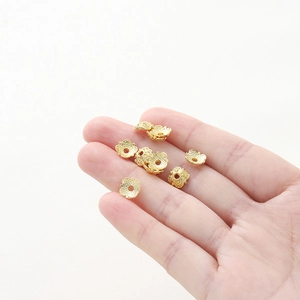 Close-up of gold hollow flower bead caps for DIY jewelry making held in hand for size
