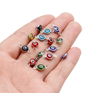 Colorful stainless steel evil eye connector pendants shown on palm for size reference
