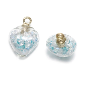 Vue macro de pendentifs en verre en forme de cœur avec paillettes bleues et anneaux dorés