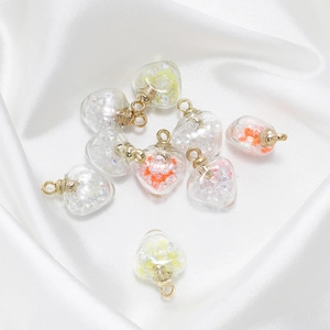Gros plan de pendentifs en verre en forme de cœur avec perles colorées sur soie blanche