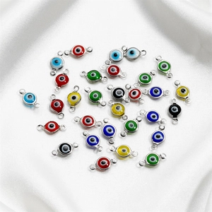 Macro shot of colorful evil eye connectors for jewelry making on white satin background