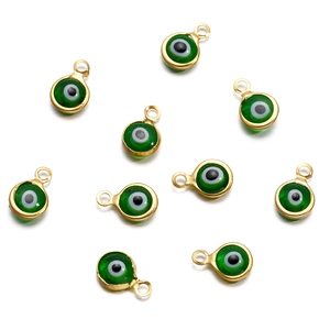 Detailed macro view of gold-rimmed green evil eye connectors for jewelry making