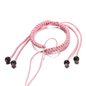 Detail van roze handgevlochten armband met verstelbare schuifknoop en zwarte ronde kralen
