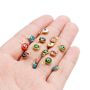 Handheld display of colorful small evil eye enamel charms for DIY jewelry making