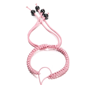 Detail van roze handgeweven armband met verstelbaar trekkoord en zwarte kralen