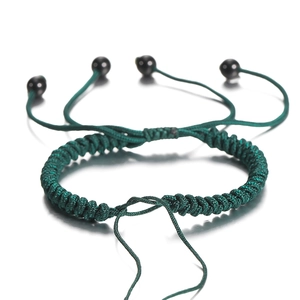 Detail van donkergroen gevlochten armband met verstelbare knoop en zwarte kralen