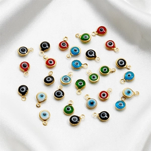Detail of colorful evil eye charms with gold frames on white silk fabric for DIY jewelry