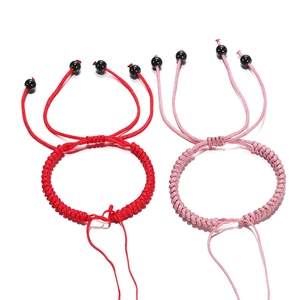 Detail van verstelbare rood en roze handgevlochten armbanden met schuifknoop en zwarte kralen