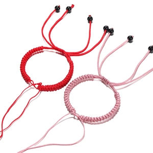 Detail van handgemaakte rode en roze geweven armbanden met zwarte schuifkralen