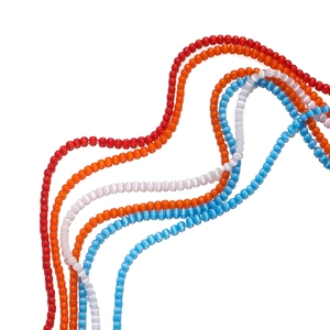 Close-up of vibrant 2mm cat-eye glass beads in red, orange, white, and blue for jewelry making