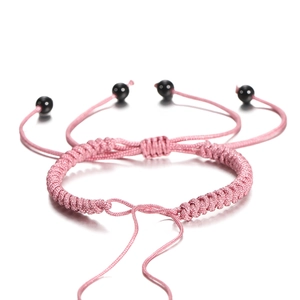 Detail van roze gevlochten armband met verstelbare zwarte kralen op een witte achtergrond
