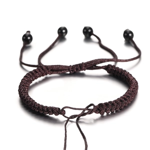 Macro-opname van donkerbruine gevlochten armband met schuifknoop en zwarte kralen