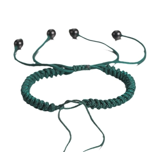 Handgemaakte donkergroene gevlochten armband met zwarte kralen op witte achtergrond