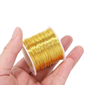 Χέρι που κρατά ρολό χάλκινου σύρματος 18K για χειροποίητα κοσμήματα DIY