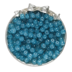 Macro shot of 8x7mm sea blue apple-shaped glass beads in a silver bow tray for DIY jewelry