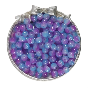 Macro detail of blue and purple gradient cylindrical glass beads in a silver bow tray