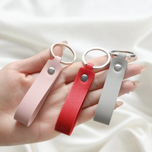 Detail of three leather loop keychains in pink, red, and grey with litchi texture