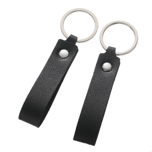 Detail of two black lychee grain leather keychains with silver metal rings on white background
