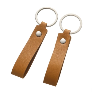 Close-up of brown litchi grain leather keychains with silver metal rivets and rings