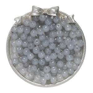 Close-up of translucent grey-blue glass apple beads in a decorative tray for DIY jewelry